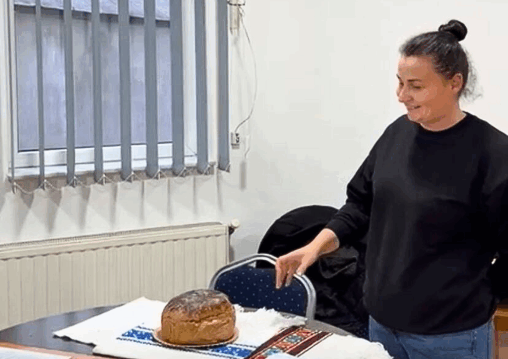 Participantă la cursul de brutărie și cofetărie ținând o tavă cu un cozonac proaspăt copt.
